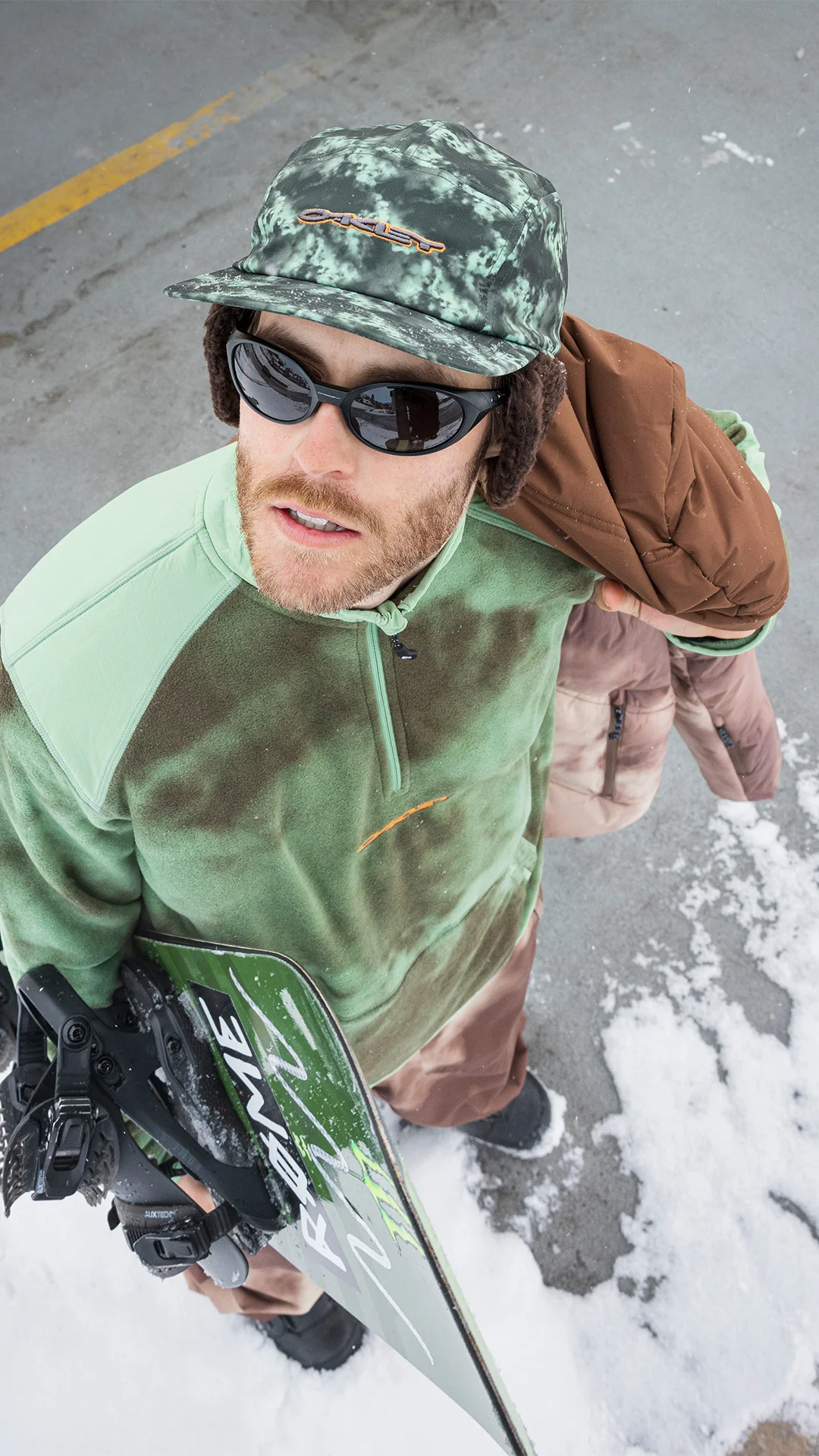 Snowboarder con occhiali da sole per la montagna Oakley

